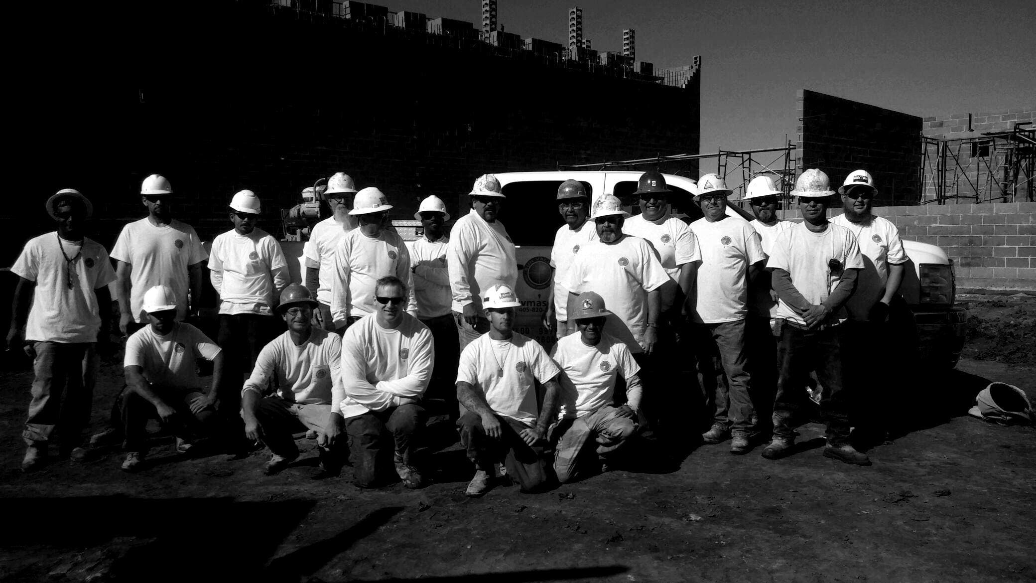 A group of construction workers wearing hard hats from Sun Valley Construction posing for a photo at a construction site.