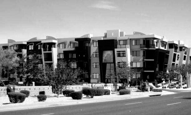 A black and white photograph of a modern multi-story residential building constructed by Sun Valley Construction beside a road with no visible pedestrians or vehicles.