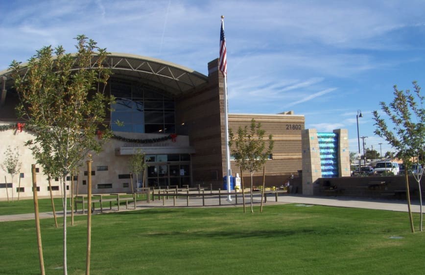 Modern public building with an american flag and manicured lawn on a clear day.