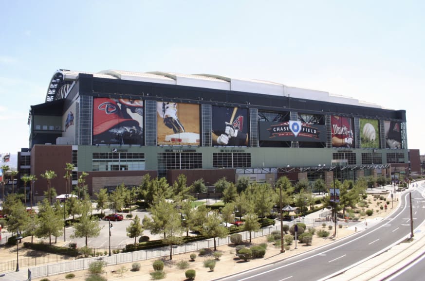 Exterior view of chase field, a baseball stadium with large banners featuring arizona diamondbacks branding, set against a clear sky.