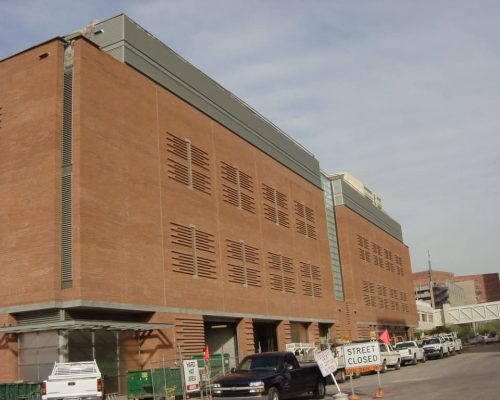 Large brick building with a pattern of vents, construction activity nearby, and a "street closed" sign visible.