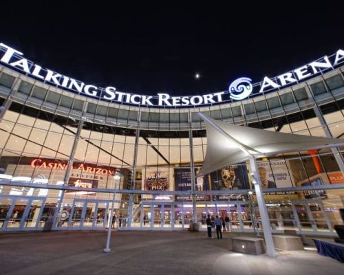 Exterior view of talking stick resort arena at twilight, showcasing its illuminated signage and entrance.