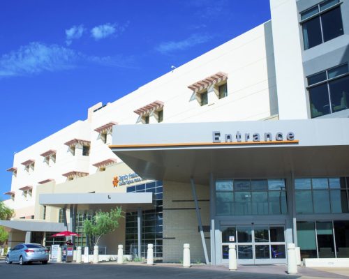 Modern building with an "entrance" sign above the door and a clear blue sky in the background.