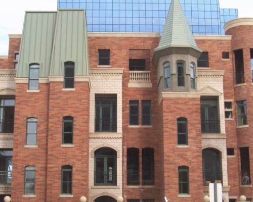 Brick building with eclectic architectural styles in front of a modern glass facade.