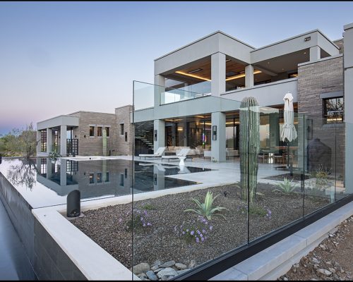 Residential luxury home with a pool at dusk.