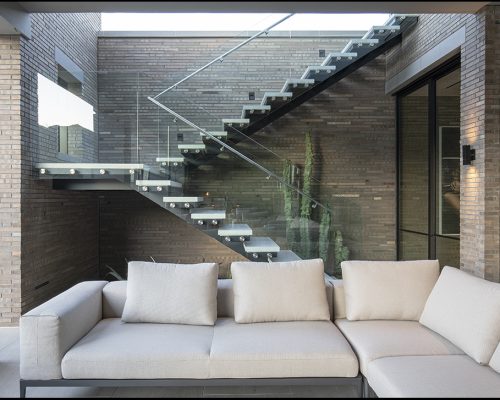 Residential living space with a sectional sofa and floating staircase design.